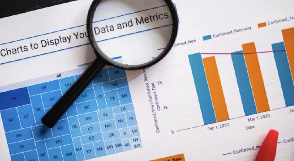 A magnifying glass resting on printed bar charts